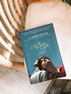 a book sitting on top of a white chair next to a wooden arm chair with a blue cover