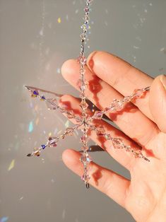 a hand holding a crystal star ornament in it's left hand,