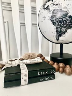 a globe sitting on top of a table next to books and wooden beads with measuring tape around it