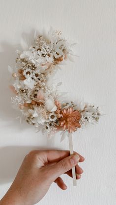 a hand holding a fake flower bouquet on top of a white wall next to a person's hand