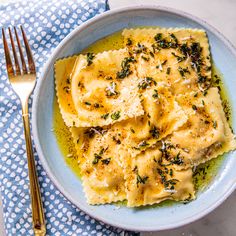 a plate of ravioli with pesto and parmesan cheese on it next to a fork