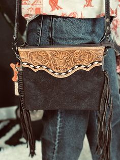 Experience rustic elegance with The Heading South Purse. Crafted from fancy tooled leather and accented with fringe and buckstitch, this purse exudes charm and Western-inspired style. Perfect for any occasion, its cute design adds a touch of playful sophistication to any outfit. Adjustable Strap Top Graphic Tees, Tooled Leather, Rustic Elegance, Cute Design, Leather Tooling, Fashion Tops, Cute Designs