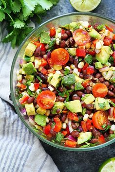 a glass bowl filled with black beans, avocado, tomatoes and cilantro