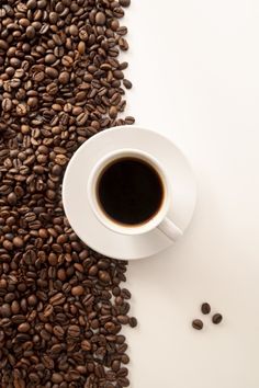 a cup of coffee sitting on top of a pile of coffee beans