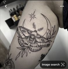 a black and white photo of a moth tattoo on the right thigh, with stars in the background