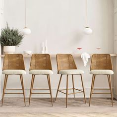 four wicker bar stools in front of a dining table with potted plant