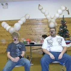 two men sitting in chairs with balloons on their heads