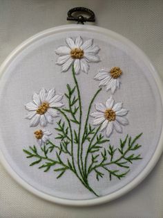 a close up of a embroidery on a white cloth with flowers in the center and green stems