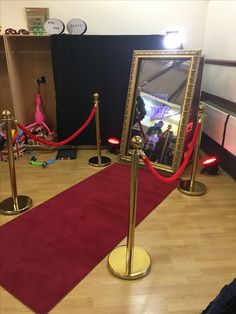 a red carpet and some gold poles with a mirror on it