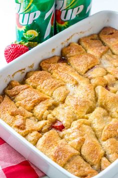 a close up of a casserole in a pan with strawberries next to it