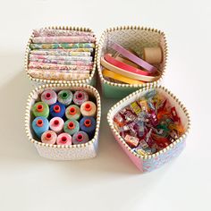 three baskets filled with different types of crafting supplies on top of a white table