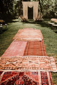 several rugs laid out on the grass with chairs in the background