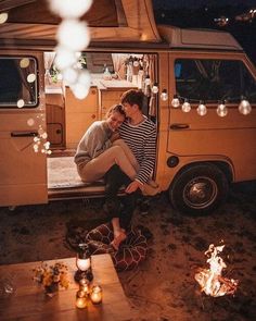 two people sitting in the back of a van at night, with lights hanging from the ceiling