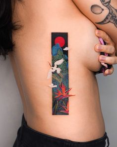 a woman with tattoos on her back holding a cell phone