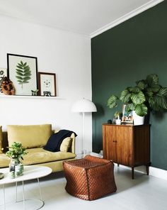 a living room filled with furniture and plants on the wall next to a table in front of it