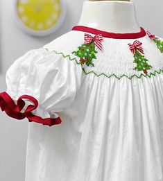 "Gorgeous, Christmas Hand smocked Christmas trees dress for your little  princess!   This dress is just beautiful with many little details.  It's fully lined. It's a long dress. Please refer to the measurements. Great for Christmas,  birthdays, photo shoots, everyday, special occasions. Color: White, red, green Material: Cotton satin  Sizes: 0-3 months: length 15\" 3-6 months: length 17\" 6-12 months: length 19 \" 12-18 months: length 20.5\" 2  years            length 23\" 3  years            le Angel Baby Clothes, Smocking Baby, Smocked Christmas Dresses, Smocked Bishop Dress, Hand Smocked Dress, Christmas Tree Dress, Smocked Clothes, Heirloom Dresses, Tree Dress