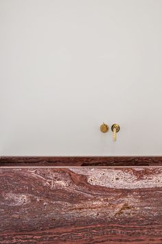 two golden knobs are on the side of a wooden cabinet with marbled surface