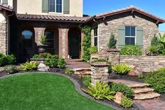 a house with landscaping in front of it and green grass on the ground next to it