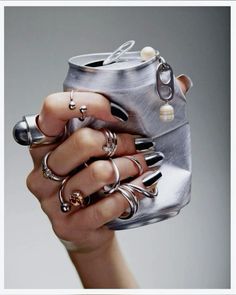 a woman's hand holding a silver can with rings on it and an open lid