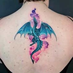 a woman's back with a blue dragon tattoo on her left shoulder and chest