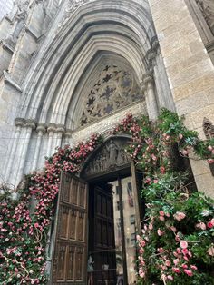 the entrance to an ornate building with pink flowers growing on it's walls and doors