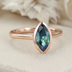 a rose gold ring with a green tourmaline stone in the center, sitting on a white cloth