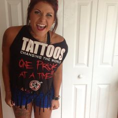 a woman with tattoos standing in front of a door wearing blue shorts and a black tank top