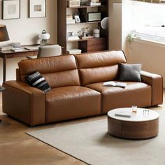 a brown leather couch sitting in a living room next to a white table and chair