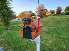 a wooden bear mailbox sitting in the grass