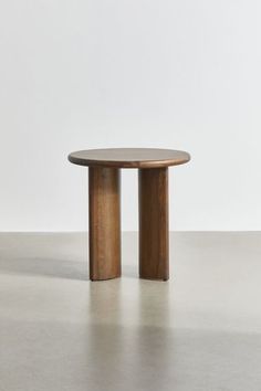 a round wooden table with two legs in the middle and one leg on the other side