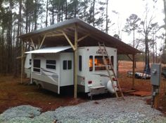 a camper parked in the woods with a ladder up to it's roof