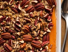 a tray filled with pecans and other nuts on top of a table next to a spoon