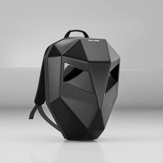 a black backpack sitting on top of a white floor next to a gray wall in the background