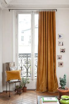 a living room filled with furniture and a window covered in yellow draping next to a wooden floor