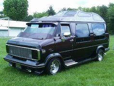 a black van parked on top of a lush green field