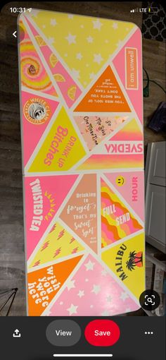 a pink and yellow refrigerator with stickers on it's side in a room