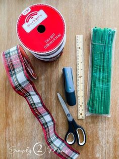 scissors, tape and other crafting supplies laid out on a wooden table next to a spool of thread