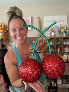 a woman holding two red ornaments in her hands