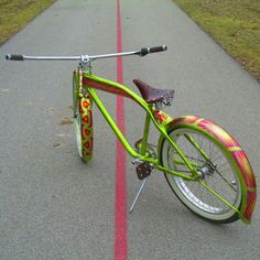 a green bicycle parked on the side of a road next to a red and white line