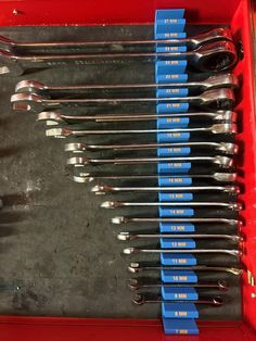 a red tray filled with lots of blue and silver utensils on top of a table