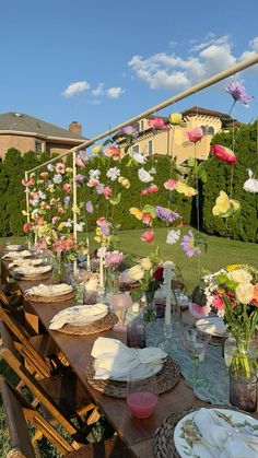 an outdoor table with plates and flowers on it