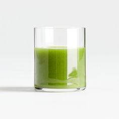 a glass filled with green liquid sitting on top of a table