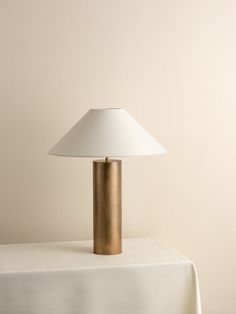 a table lamp sitting on top of a white cloth covered table next to a wall