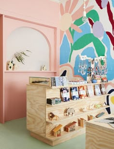 the interior of a store with pink walls and colorful artwork on the wall behind it