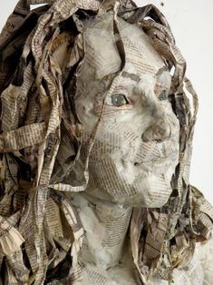 a sculpture made out of newspaper paper with a woman's face and hair in the middle