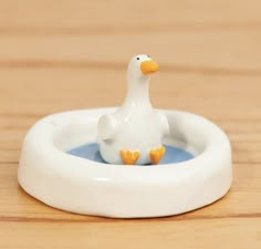 a small white duck floating in a bowl