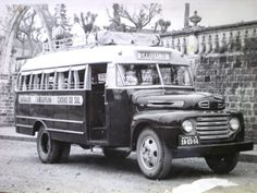 an old black and white photo of a bus parked in front of a brick wall