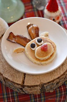 a white plate topped with pancakes and bacon on top of a wooden table next to a teddy bear