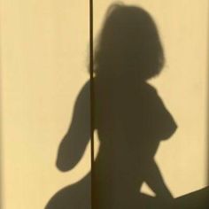 the shadow of a woman standing in front of a wall