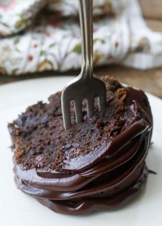 a fork stuck into a chocolate cake on a plate